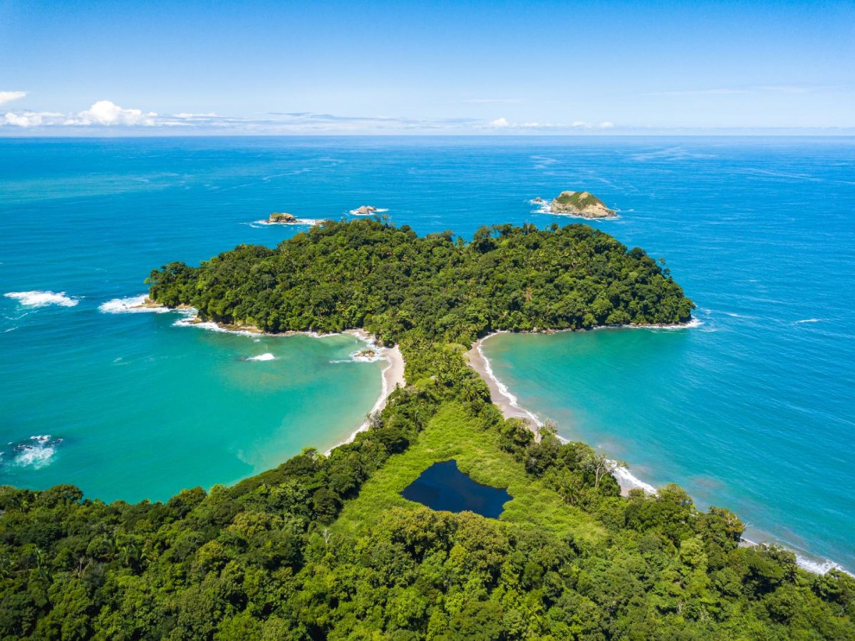Aerial view of a lush, green peninsula with turquoise waters and white sandy beaches surrounded by small islands.